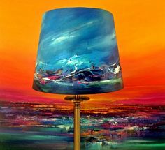 a blue lamp sitting on top of a wooden table next to a painting with an orange sky in the background