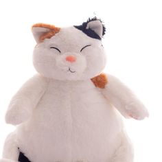 a white cat stuffed animal sitting on top of a white surface with its eyes closed