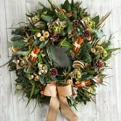 a wreath is hanging on the wall with pine cones and greenery around it's edges