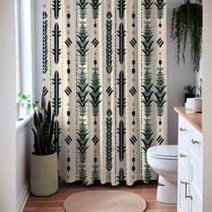 a white toilet sitting next to a shower curtain in a bathroom with plants on the wall