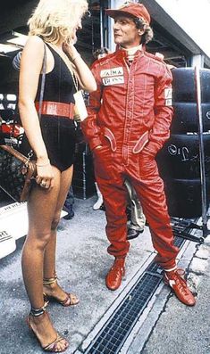 a man in a red racing suit talking to a woman wearing a black bathing suit