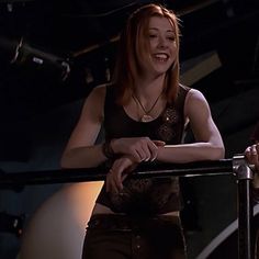 two young women standing next to each other in front of a metal railing and smiling