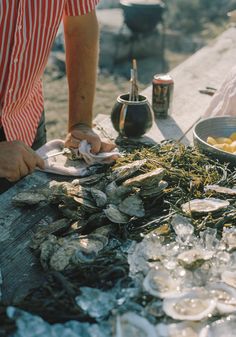 a man standing next to a table filled with oysters and other food on top of it