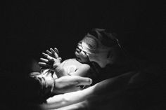 a black and white photo of a woman holding a baby in her arms with both hands