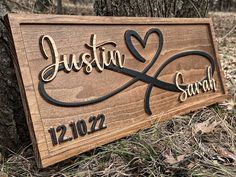 a wooden sign with the name and date engraved on it in front of a tree