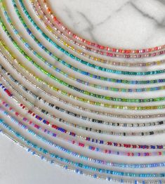 multicolored glass beaded necklaces on a marble surface