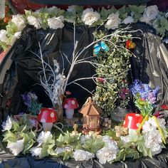 the trunk of a car is covered with flowers and plants, including mushrooms, trees, and small houses