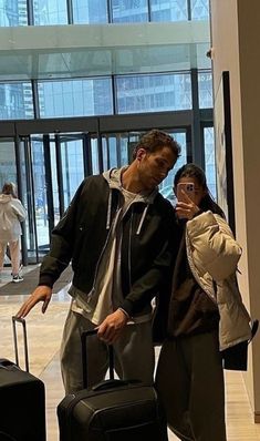 a man and woman standing next to each other with their luggage in front of them