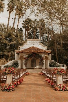 an outdoor ceremony setup with chairs and flowers on the aisle, surrounded by palm trees