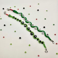 a green beaded name bracelet with black and white letters on it, surrounded by beads