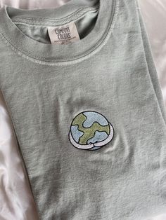 "Embroidered Earth Hug T-Shirt l Comfort Colors Minimalist T-Shirt -Embroidered on 100% Cotton, Comfort Colors Brand T-shirts. This design is simple and minimalistic, perfect for every outfit!  -Embroidery design measures 2\"x3\" -See product pictures for shirt sizing chart. These t-shirts run true to size, so if you like an oversized look, we recommend sizing up 1 size!  -All t-shirt designs are handmade on an embroidery machine so there may be slight differences, but we only sell the shirts th Everyday Crew Neck Tops With Embroidered Graphics, Crew Neck Top With Embroidered Graphics For Everyday, Casual Embroidered Tops For Everyday, Green Casual T-shirt With Embroidered Text, Relaxed Fit T-shirt With Embroidered Graphics For Everyday, Casual Embroidered Everyday T-shirt, Oversized Casual Embroidered T-shirt, Basic Embroidered Text T-shirt For Everyday, Casual Everyday Embroidered T-shirt