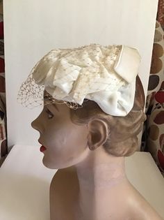 "Vintagw 1950's 1960's Off White hat with veiling. Has an Off White Velvet bow in the back. *MORE INFORMATION BELOW* CONDITION: I note a hole in the veiling on the left side (SEE PIX). Also a split in the veiling on the right side (SEE PIX). Sold As Is! MEASURES: Left to right UP and OVER the hat~12\" Front to back~7\" *WE APOLOGIZE~BUT WE NO LONGER SHIP TO GERMANY, ITALY OR SPAIN. IF ORDERS COME IN FROM GERMANY, ITALY OR SPAIN, WE WILL HAVE TO CANCEL THEM AND REFUND YOUR MONEY. SORRY FOR THIS I 1960s Hats, Vintage Clothing Boutique, Flower Corsage, Pillbox Hat, White Velvet, White Hat, Velvet Bow, Vintage 1950s, Right Side