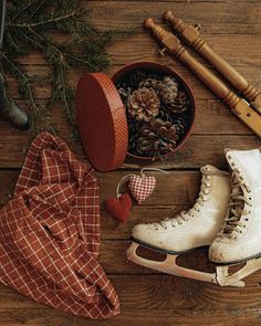 an old pair of ice skates sitting on top of a wooden floor next to pine cones