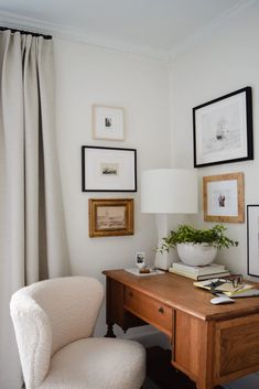 a white chair sitting in front of a wooden desk with pictures on the wall behind it