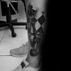 a black and white photo of a man's leg with chess pieces on it