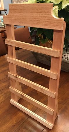 a wooden rack sitting on top of a hard wood floor next to a potted plant