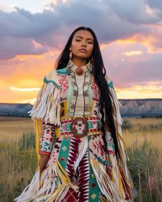 a native american woman standing in a field at sunset