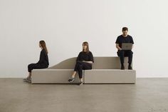 three people sitting on a couch with laptops in their hands and one person standing behind them