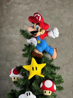 a christmas tree with mario and other toys on it's top, sitting in front of a wall