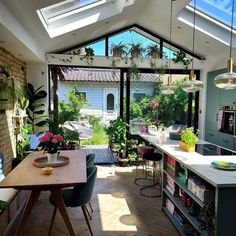 an open kitchen and dining room area with skylights above the counter top, potted plants on shelves below