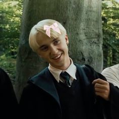 two young men dressed in harry potter costumes, one with blonde hair and the other wearing a pink bow