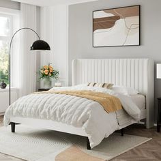 a white bed sitting in a bedroom on top of a hard wood floor next to a window