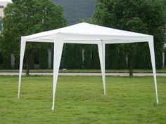 a large white tent sitting on top of a lush green field with trees in the background