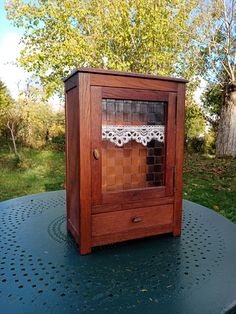 a small wooden cabinet sitting on top of a table in the middle of a yard