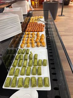 there are many different foods on the trays at this buffet table, including pickles and other food items