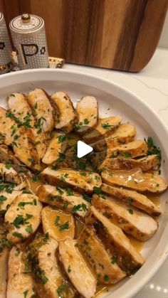 a white bowl filled with sliced chicken and garnished with parsley on top