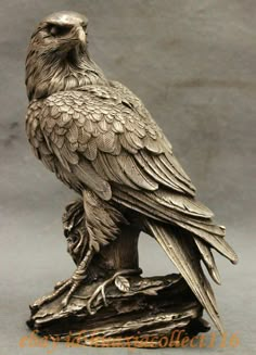 a statue of an eagle sitting on top of a piece of wood