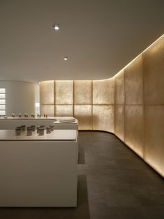 an empty kitchen with white counter tops and lights on the wall behind it, along with wooden paneling