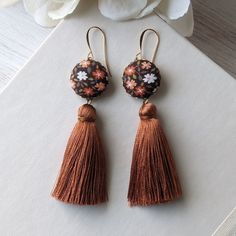 "Embody the fun vibes of the 1970s with these unique retro earrings - they're handmade with vintage fabric with a pretty floral print in shades of orange, brown, white, and green, with shiny and silky burnt orange tassels that hang below. You'll love the boho charm these earrings will add to your contemporary look, and how comfortable and lightweight they are, as well.  To complete the look, the earrings include hypoallergenic and nickel-free gold-plated brass earwires that provide a touch of elegance and ensure comfortable wear throughout the day. They'll also include small, clear rubber backings. Details: Full length - almost 3.5 inches (8.8 cm) Width of floral piece - 3/4\" (1.9 cm) Earring hooks - gold plated brass, hypoallergenic and nickel-free  Similar jewelry: Check out my shop for Vintage Brown Earrings For Festivals, Retro Dangle Earrings For Festivals, Vintage Latkans Earrings For Party, Vintage Tassel Jewelry For Festival, Vintage Multicolor Latkan Earrings, Bohemian Fall Fashion, 70s Earrings, Fall Fashion Accessories, Fun Vibes