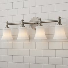 four light bathroom fixture with white glass shades on the wall and brick tile back splash