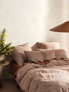 a bed with brown and white checkered comforter next to a table with yellow flowers