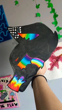 someone holding up a piece of art that looks like a bear with a rainbow on it