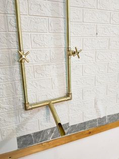 a pair of gold square shaped mirrors mounted on a wall next to a white brick wall