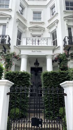 a large white building with lots of windows and plants growing on the side of it