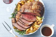 roast beef and potatoes on a platter with two glasses of wine