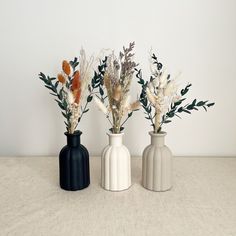 three vases with flowers in them sitting on a table