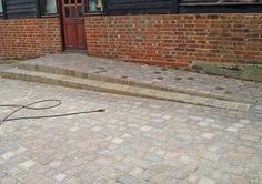 a fire hydrant sitting on the side of a brick road next to a building