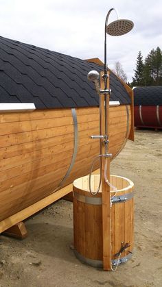 a large wooden barrel sitting next to a building with a shower head on it's side