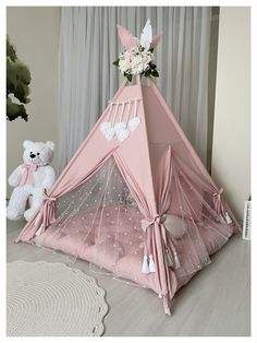 a pink teepee with white polka dots and flowers on the top is next to a teddy bear