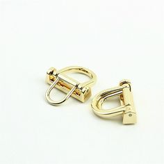 two pairs of gold colored metal clips on a white background with clippings in the middle