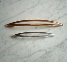 two metal pins sitting on top of a white marble counter