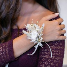 a woman wearing a purple dress holding a white wrist corsage