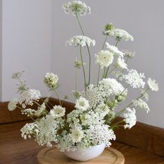 a vase filled with white flowers on top of a wooden table