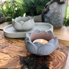 a candle sits on a wooden table next to two plates with plants in the background