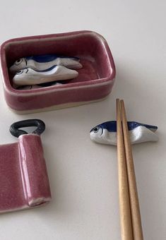 three bowls and two chopsticks are on the table with some fish figurines in them