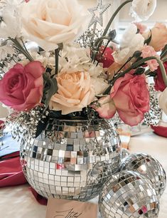 a vase filled with lots of flowers sitting on top of a table next to disco balls